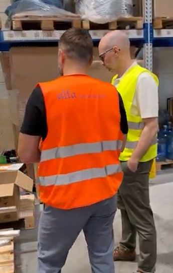 Pracownicy w kamizelkach ostrzegawczych podczas obchodu hali magazynowej Alfa Warehouses