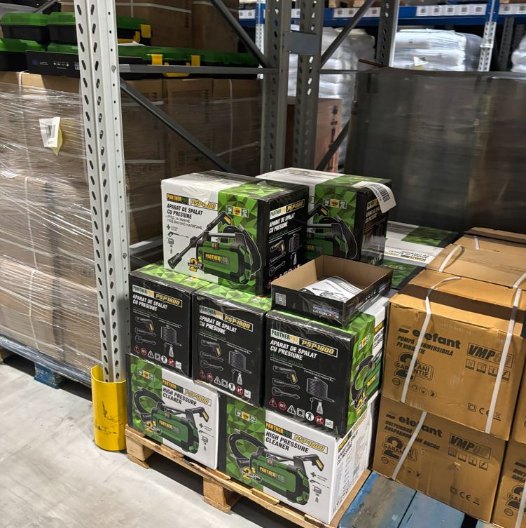 Towar klienta BEM ułożony na paletach przy regałach magazynowych w hali Alfa Warehouses